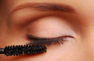 Woman applying black mascara on the eyelashes. Close-up image.